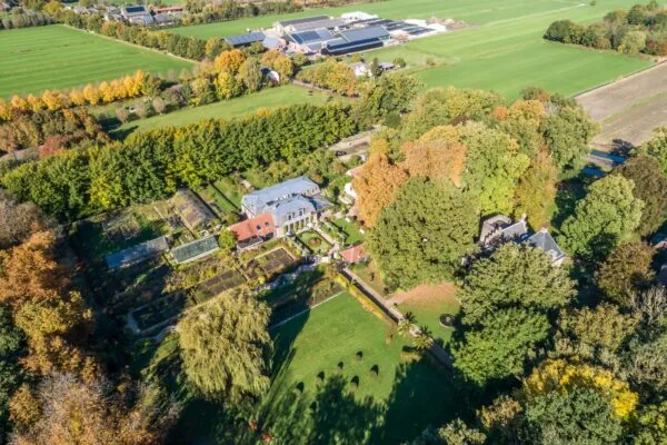 Luchtfoto van een landgoed met moestuin en siertuin aan de Langbroekerdijk A, omringd door groen en landbouwvelden.